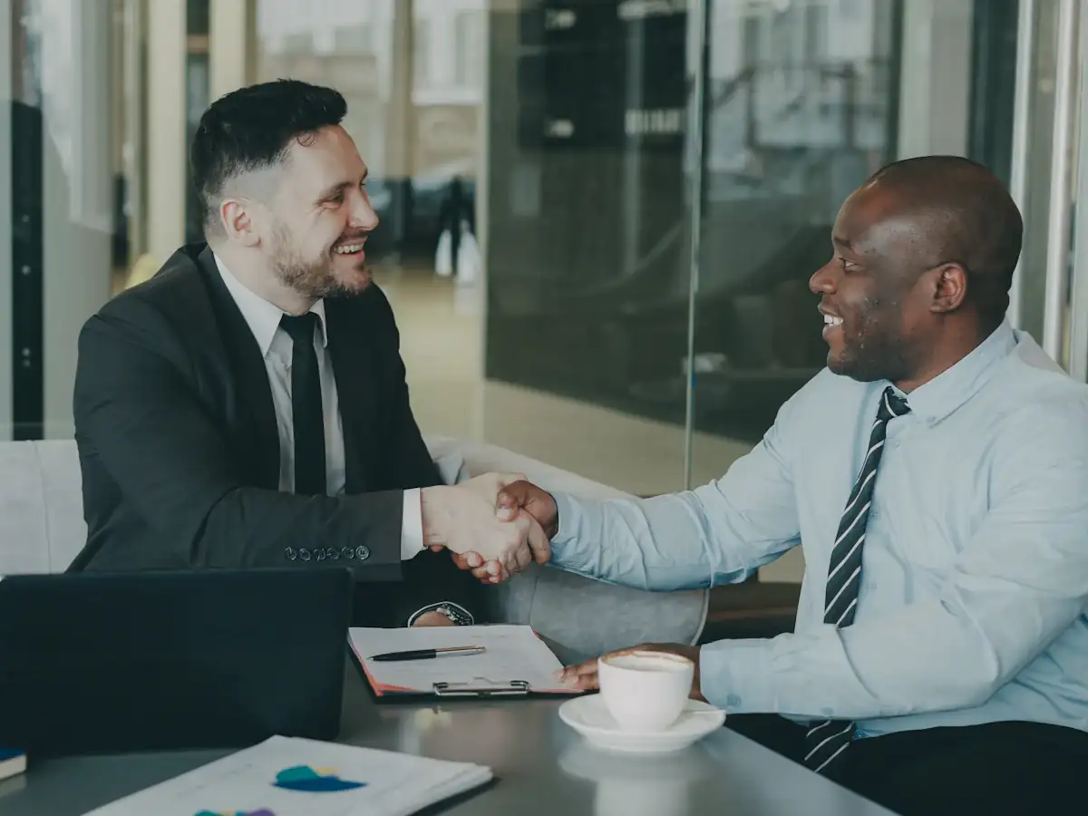 Two business people shaking hands across a meeting table