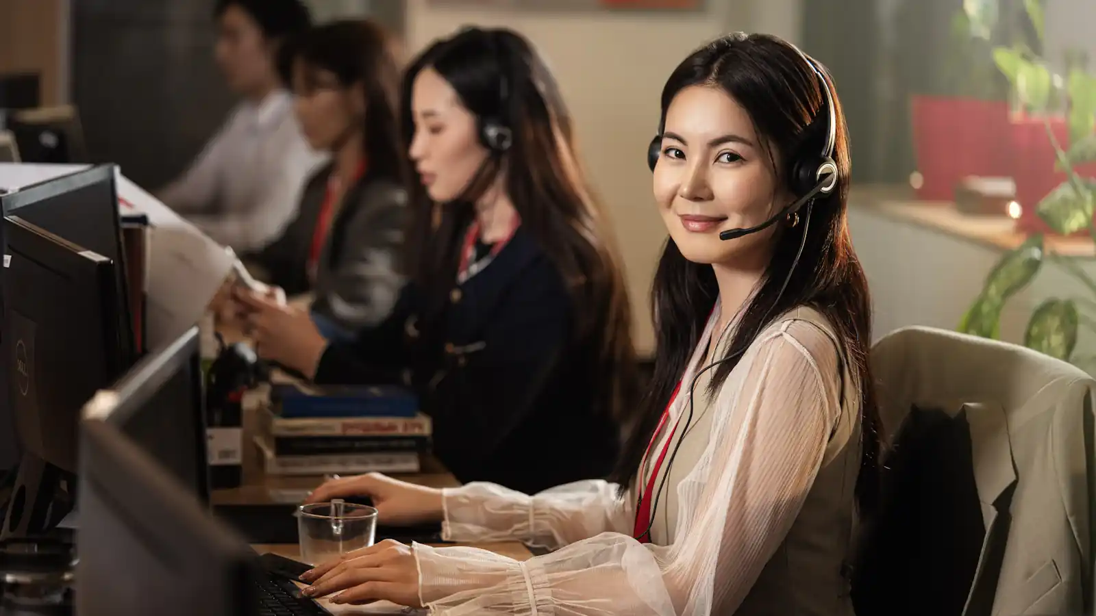 Smiling support specialist wearing a headset at a computer