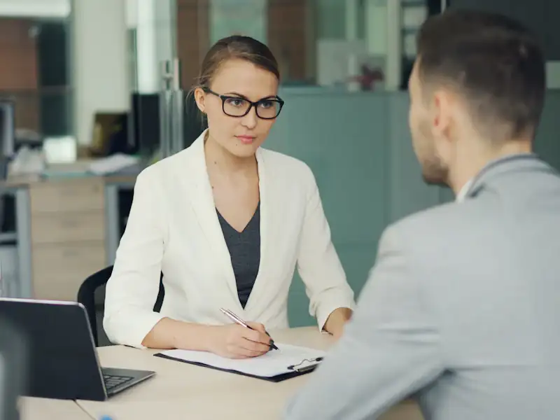 Recruiter in glasses interviewing a candidate across an office desk