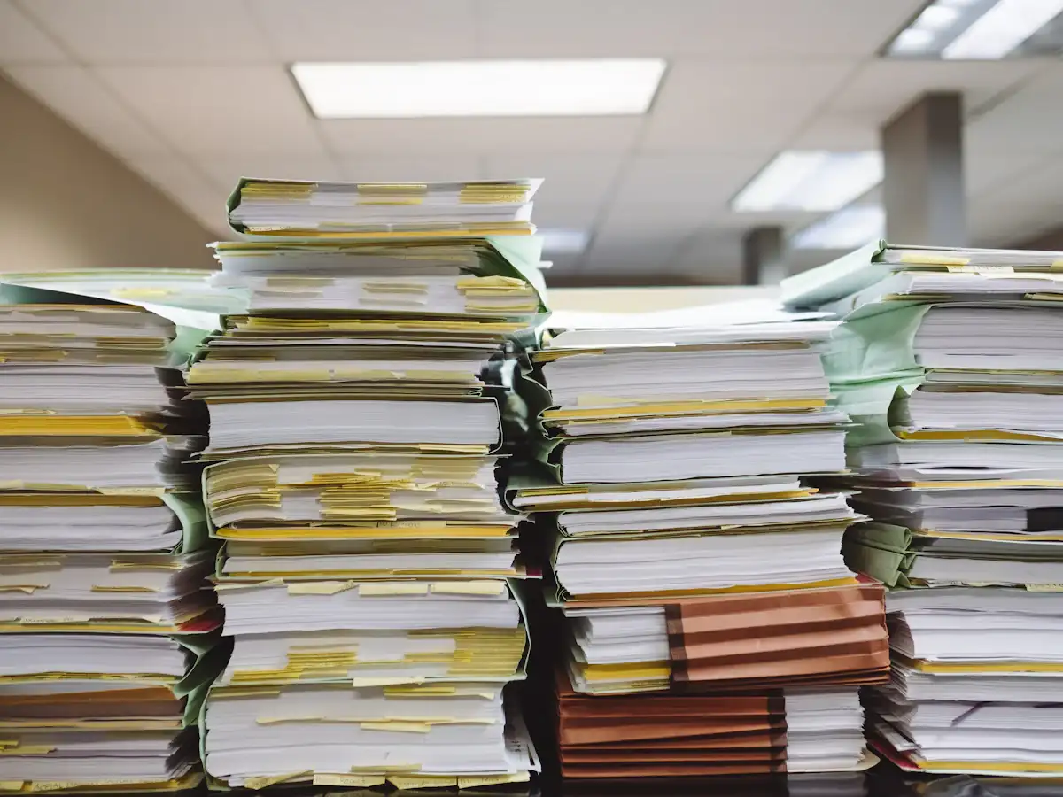 Stacks of paper documents and file folders on a desk