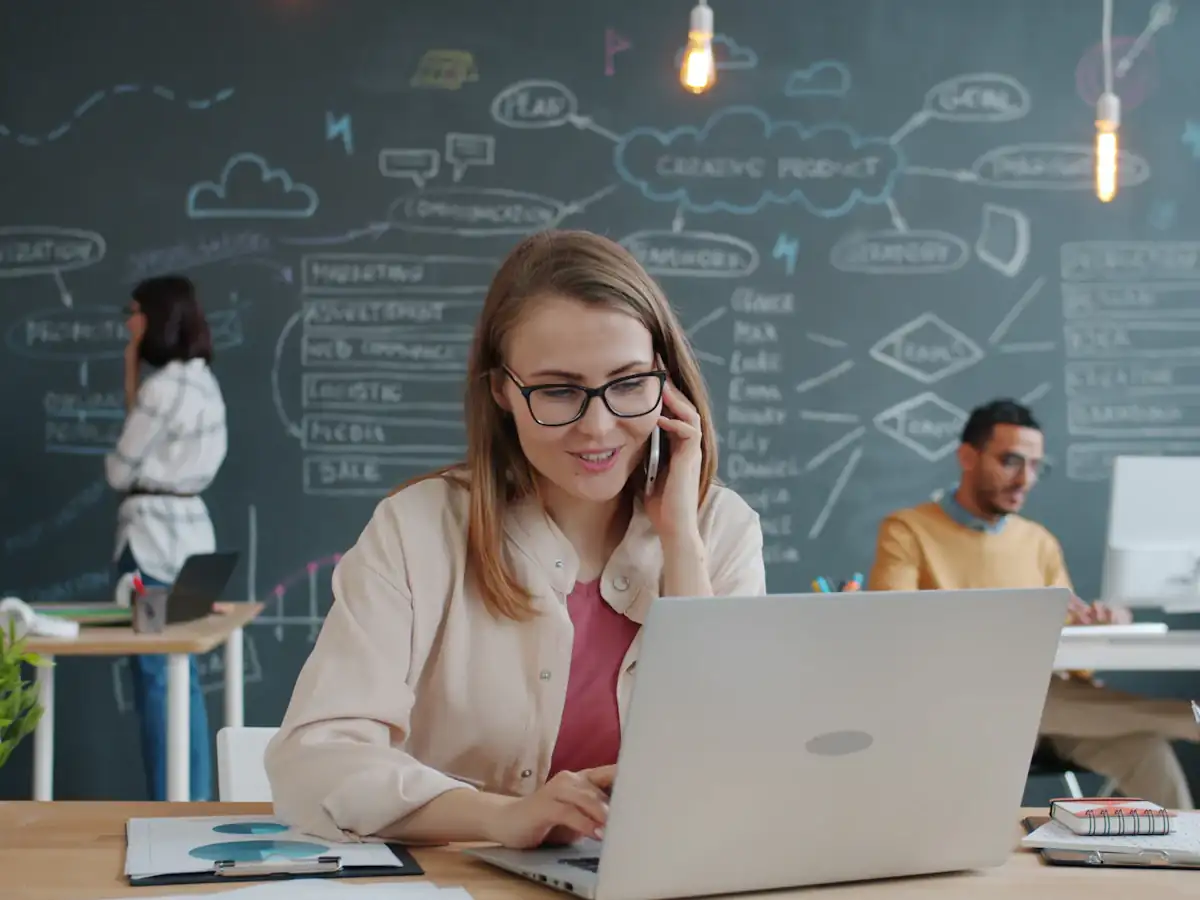Recruiter on the phone while working on a laptop in a modern office